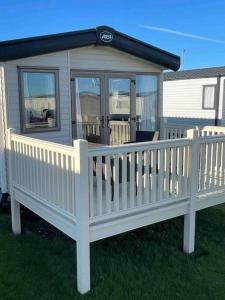 uma casa com uma cerca branca e um alpendre em The Fairways Hideaway - Northumberland em Newbiggin-by-the-Sea