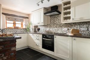 a kitchen with white cabinets and black appliances at The Old Rectory Cottages in Kings Nympton