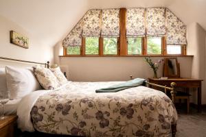 a bedroom with a bed and two windows at The Old Rectory Cottages in Kings Nympton