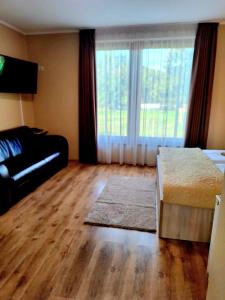 a living room with a bed and a large window at Angyal Apartman Gyula in Gyula