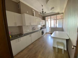 a large kitchen with white cabinets and a table at Narke Hostel in Bishkek