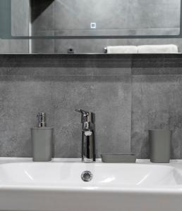 a bathroom sink with a faucet and two cups on it at Urban Elegance by Eagles' Bridge in Sofia