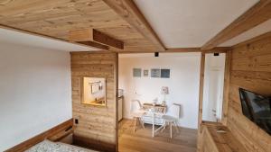 Guest House Dolomiti في باسيلغا دي بيني: غرفة بجدران خشبية وطاولة مع كراسي