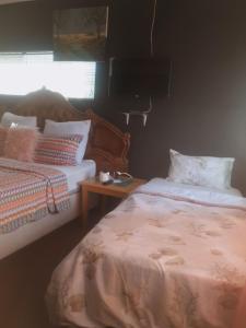 um quarto com 2 camas, uma mesa e uma janela em Randgate guesthouse em Randfontein