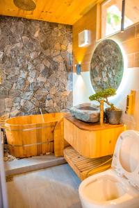 a bathroom with a wooden tub and a stone wall at Chien's Lodge Du Gia in Làng Cac