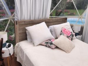 a bed with white pillows and pink flowers on it at Flowerhaven - glamping dome in Hamilton