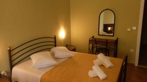 カラブリタにあるGuesthouse Eleftheriosのベッドルーム1室(白い枕と鏡付きのベッド2台付)