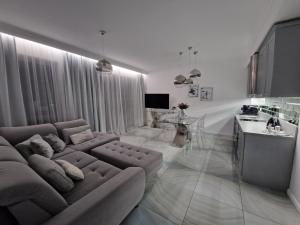 Maxim Apartment Pobierowo في بوبيروفو: غرفة معيشة مع أريكة كبيرة ومطبخ