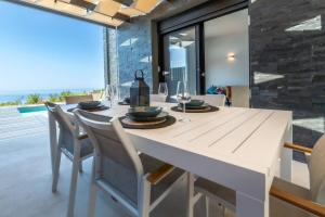 a dining room with a white table and chairs at Villa Vista Mare Lourdata Kefalonia in Lourdhata
