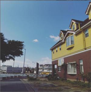 宮古島サイクリストの宿 في جزيرة مياكو: منزل اصفر على جانب شارع
