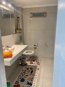 La salle de bains est pourvue d'un lavabo, de toilettes et d'un tapis. dans l'établissement Peacefull, Private, Pristine Studio Apartment, à Bodrum City