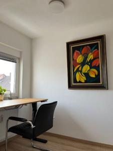a desk with a chair and a painting on the wall at Ferienwohnung in Donaueschingen