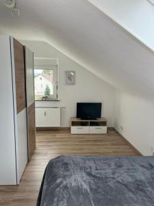 a white room with a bed and a television at Ferienwohnung in Donaueschingen