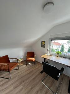 a living room with a desk and chairs and a window at Ferienwohnung in Donaueschingen