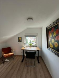 una habitación con una mesa, una silla y una pintura en Ferienwohnung en Donaueschingen