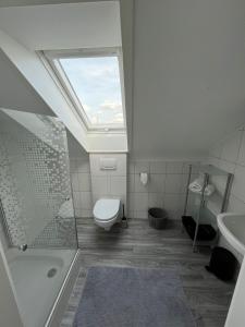 uma casa de banho com um WC, um lavatório e uma clarabóia em Ferienwohnung em Donaueschingen