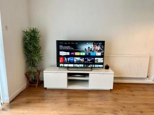 a flat screen tv sitting on a white entertainment center at Convenient Manchester city centre 3BD with free parking in Manchester