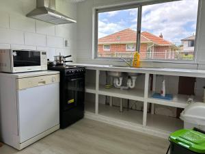 a kitchen with a sink and a microwave at Avondale Tidy Unit 1 in Auckland