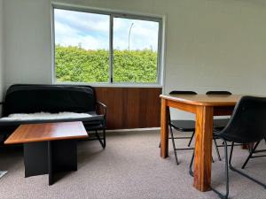 a waiting room with a table and chairs and a window at Avondale Tidy Unit 1 in Auckland