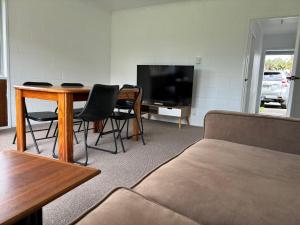 a living room with a couch and a table and a tv at Avondale Tidy Unit 1 in Auckland