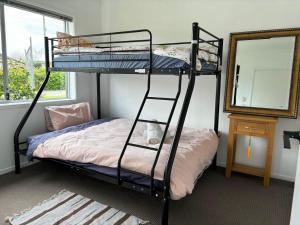 a bedroom with two bunk beds and a mirror at Avondale Tidy Unit 1 in Auckland