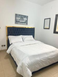 1 cama grande con sábanas blancas y cabecero azul en Ulili 1br apts Makepe, en Douala