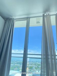 ein Fenster mit grauen Vorhängen und blauem Himmel in der Unterkunft Condo in Azure Urban Resort Residences-Paranaque City in Manila