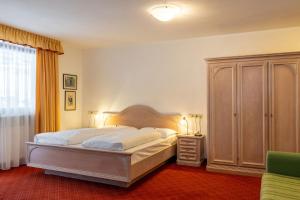 um quarto com uma cama grande e uma cómoda em Hotel Schopfenhof em San Candido