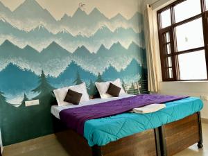 um quarto com uma cama com um mural de montanha na parede em Joey's Homestay em Rishikesh