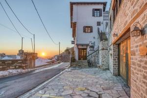 una calle vacía con un edificio y la puesta de sol en el fondo en Makrinitsa Village en Makrinítsa