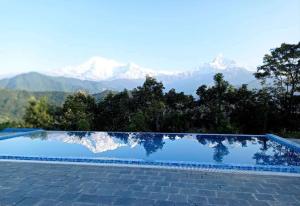 a swimming pool with mountains in the background at Himalayan Deurali Resort in Pokhara