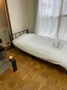 1 dormitorio con 1 cama con sábanas blancas y ventana en カプリス豊平公園201号室, en Toyohira