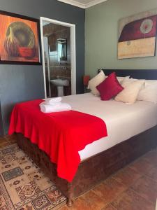 um quarto com uma cama grande e um cobertor vermelho em Marion Lodge em Joanesburgo