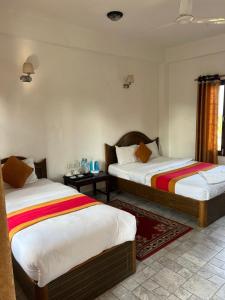 a bedroom with two beds and a room with two tables at Sauraha BnB in Sauraha