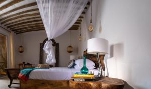 1 dormitorio con 1 cama y 1 mesa con lámpara en Infinity Beach Boutique Hotel & SPA, en Matemwe