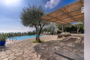 un patio con una mesa y un árbol junto a una piscina en Villa Chez Piè with Heated Infinity Pool, en SantʼAgata sui Due Golfi