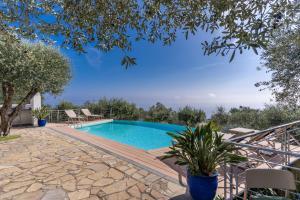 a swimming pool with a wooden deck next to a house at Villa Chez Piè with Heated Infinity Pool in SantʼAgata sui Due Golfi