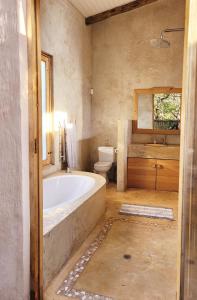 a bathroom with a tub and a toilet and a sink at Tchagra House in Hluhluwe