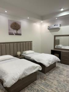 ein Schlafzimmer mit zwei Betten und einem Spiegel in der Unterkunft بودل روز للشقق المخدومة in Abha