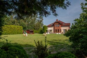 una casa con un gran patio con sillas delante en Villa Sol, en Grzybowo