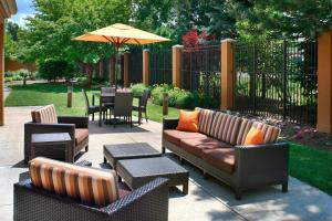 a patio with couches and tables and an umbrella at Courtyard Toledo Maumee/Arrowhead in Maumee