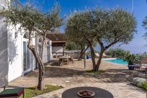 a patio with a table and trees next to a pool at Villa Chez Piè with Heated Infinity Pool in SantʼAgata sui Due Golfi