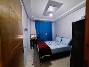 a bedroom with a bed with a blue curtain and a door at Chambre calme et relaxante à centre ville Agadir in Agadir