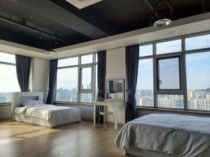 a bedroom with two beds and large windows at YD Residence in Seoul