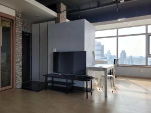 a living room with a tv and a desk with a table at YD Residence in Seoul
