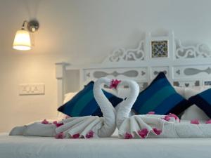 Dos cisnes hechos de toallas en una cama en Oceanic - Luxury Boutique Hotel, en Palolem