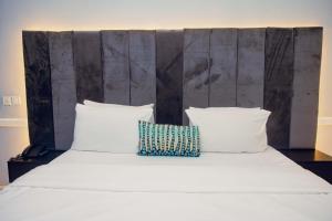 - un grand lit blanc avec 2 oreillers dans l'établissement OVIC Hotel, à Benin City