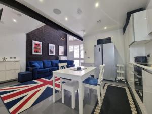 Deluxe Townhouse Zone 1 Brick Lane في لندن: مطبخ وغرفة معيشة مع طاولة وكراسي بيضاء