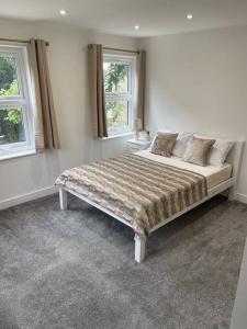 a bedroom with a large bed with two windows at Lovely Two Bedroom House in Central Kidlington in Kidlington