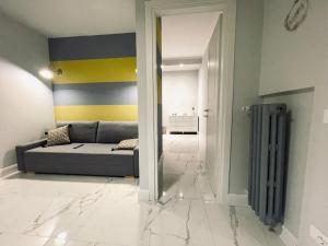 een woonkamer met een grijze bank en een gele en blauwe muur bij Vatican Tiny House in Rome